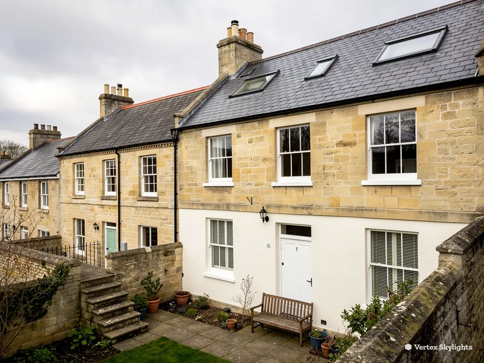 A row of honey-coloured stone cottages with slate roofs, one carrying two slim rooflights