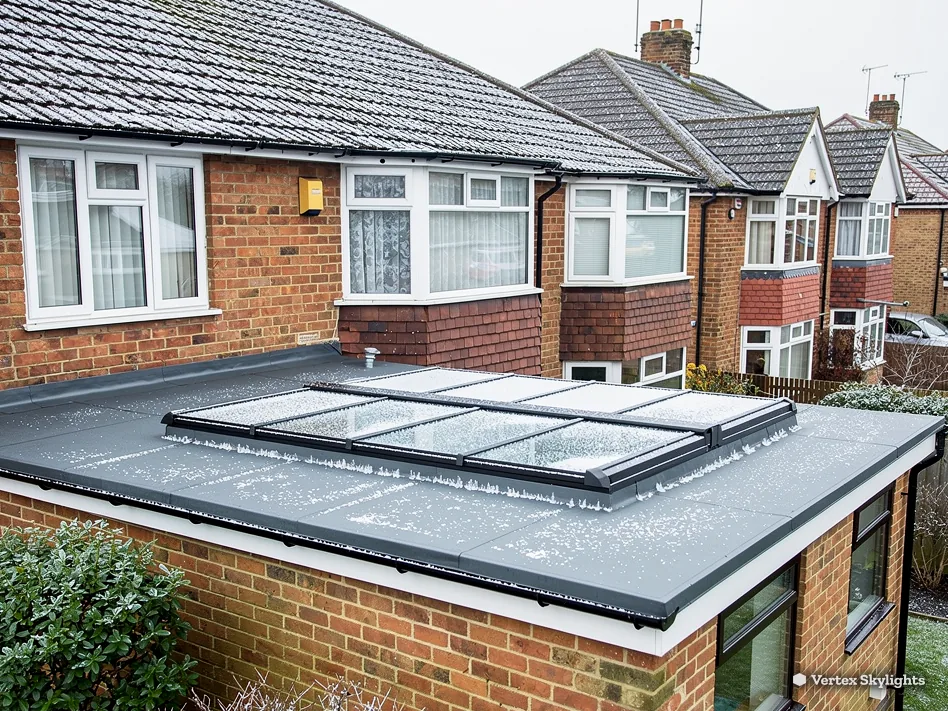 A long flat rooflight on a single-storey brick extension behind a row of semis
