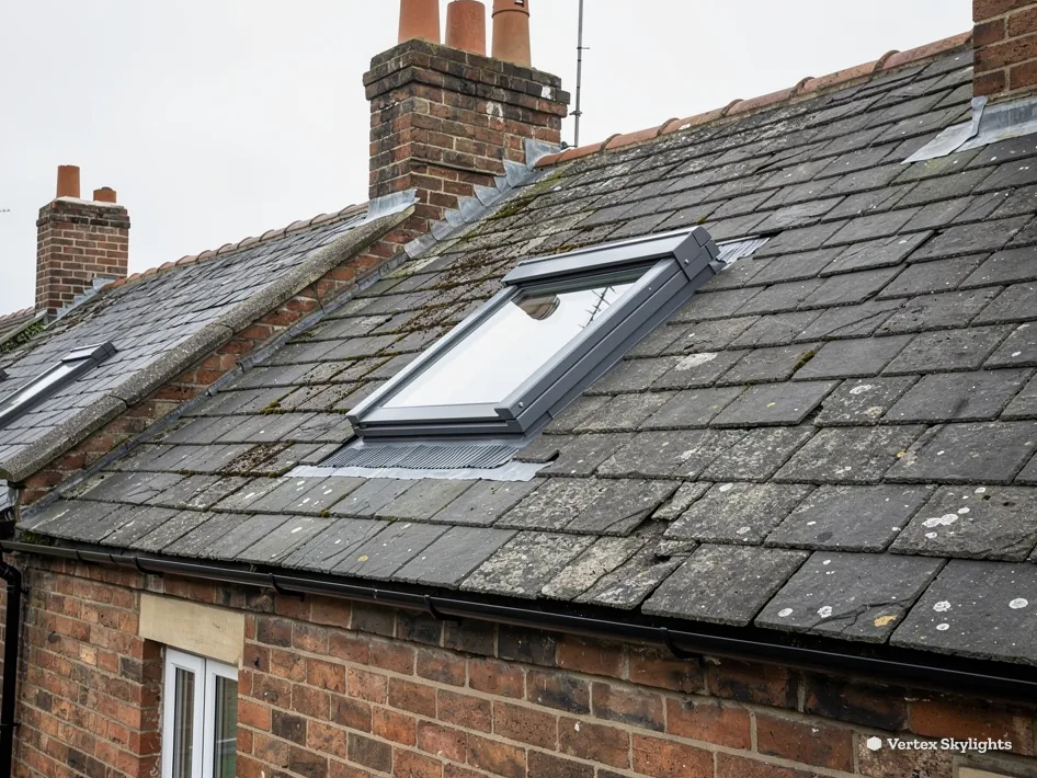 Roof windows in an old slate roof above brick walls