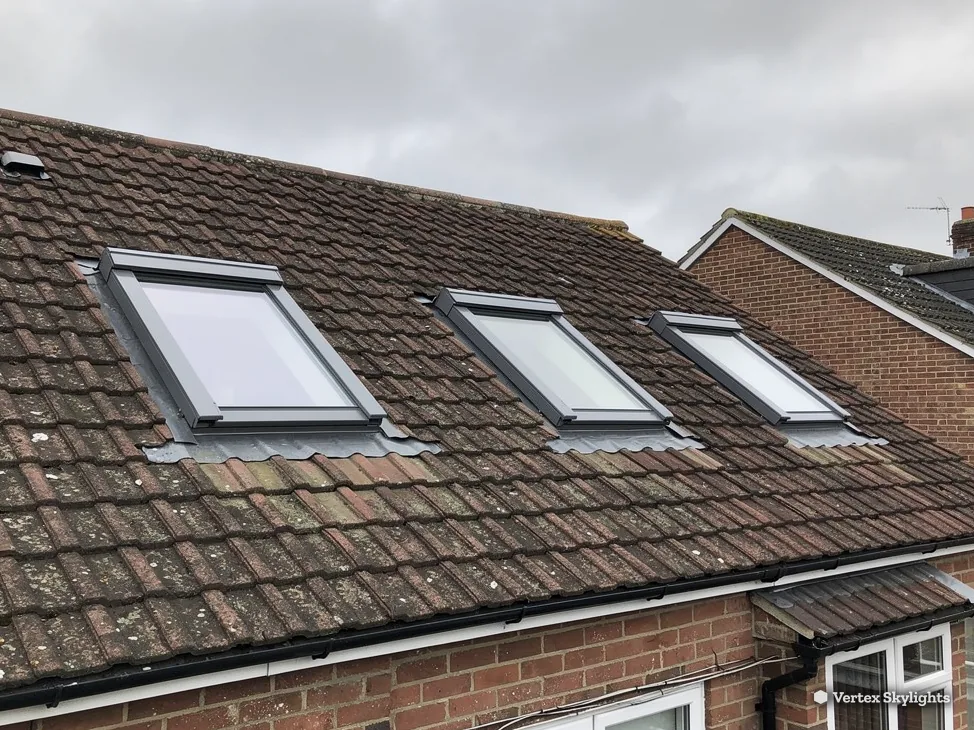 Three roof windows in a brown tiled roof