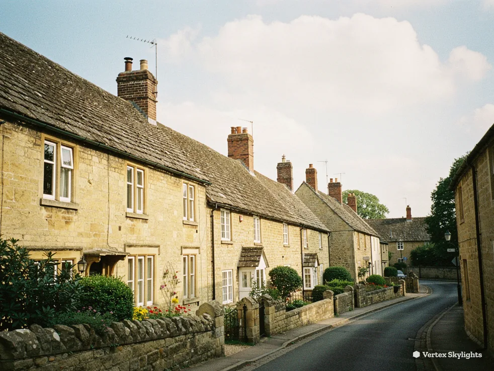 A lane of pale stone cottages with front gardens and stone walls