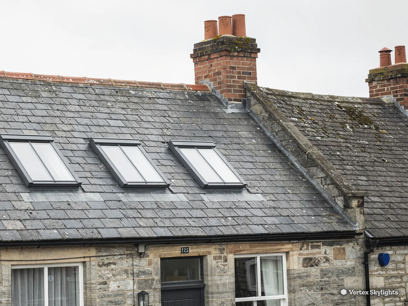 Three slim rooflights in the slate roof of a stone cottage