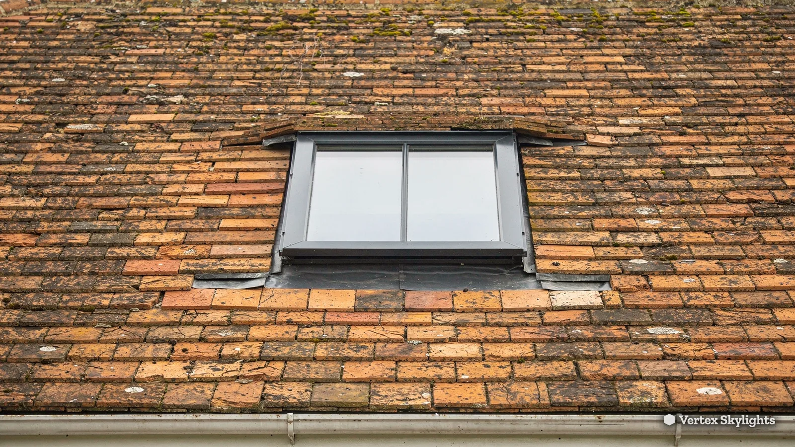 A slim rooflight set into a weathered clay tile roof