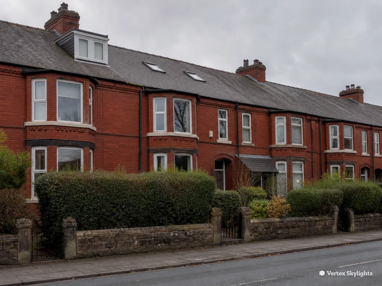 A street of red brick terraced houses with bay windows and front hedges