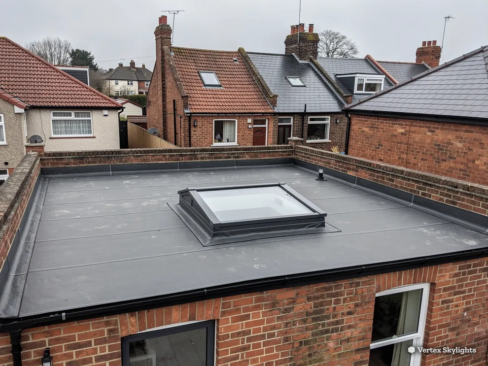 A flat rooflight on a single-storey extension between brick houses